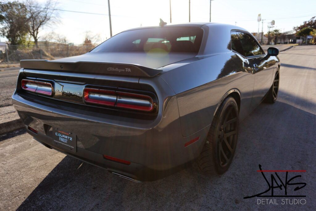 Gray Dodge Challenger R/T parked on an asphalt road; sunny day.