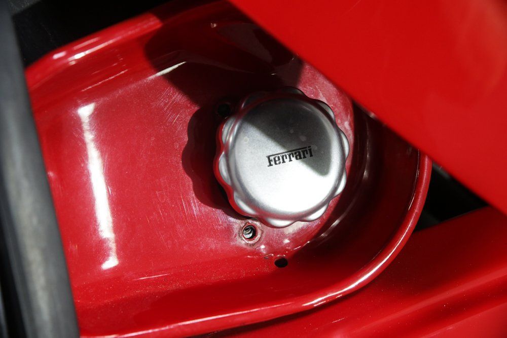 Silver Ferrari cap on red car component.