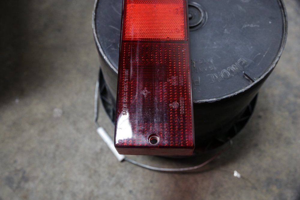 Red rectangular car tail light on a dark bucket; a clear surface.