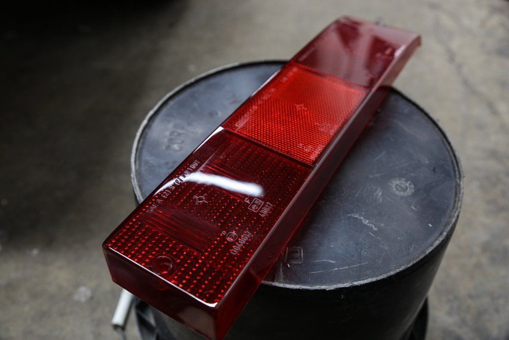 Red taillight lens on a black bucket, showing three rectangular sections of various textures.