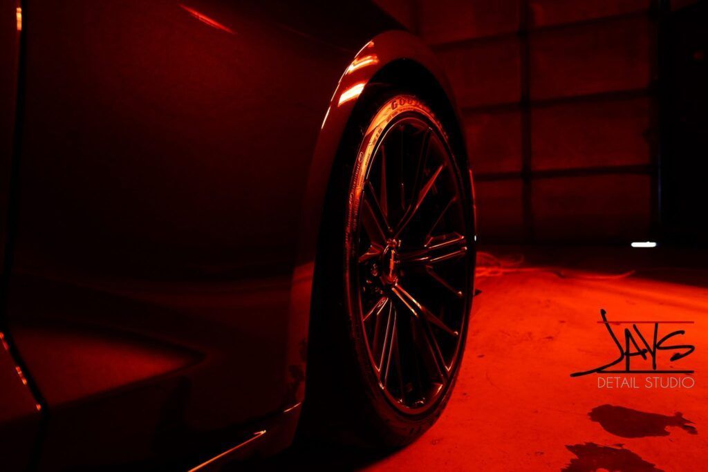 Red-lit car wheel and fender; dark setting.