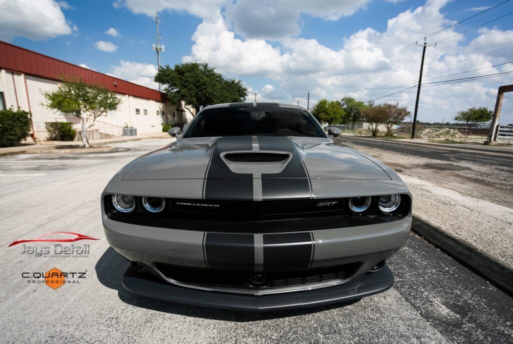 Gray Dodge Challenger with black stripes on a sunny day.