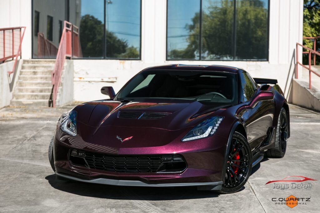 Dark purple Corvette sports car parked in front of a building.