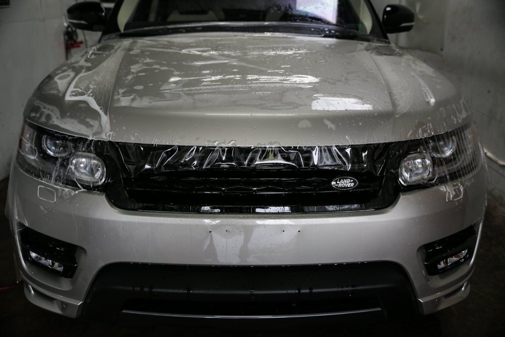 Silver Range Rover being washed; water cascading over the hood.