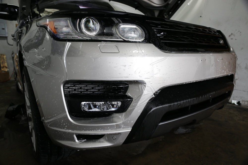 Silver Range Rover Sport, close up of front with the hood open, being worked on.