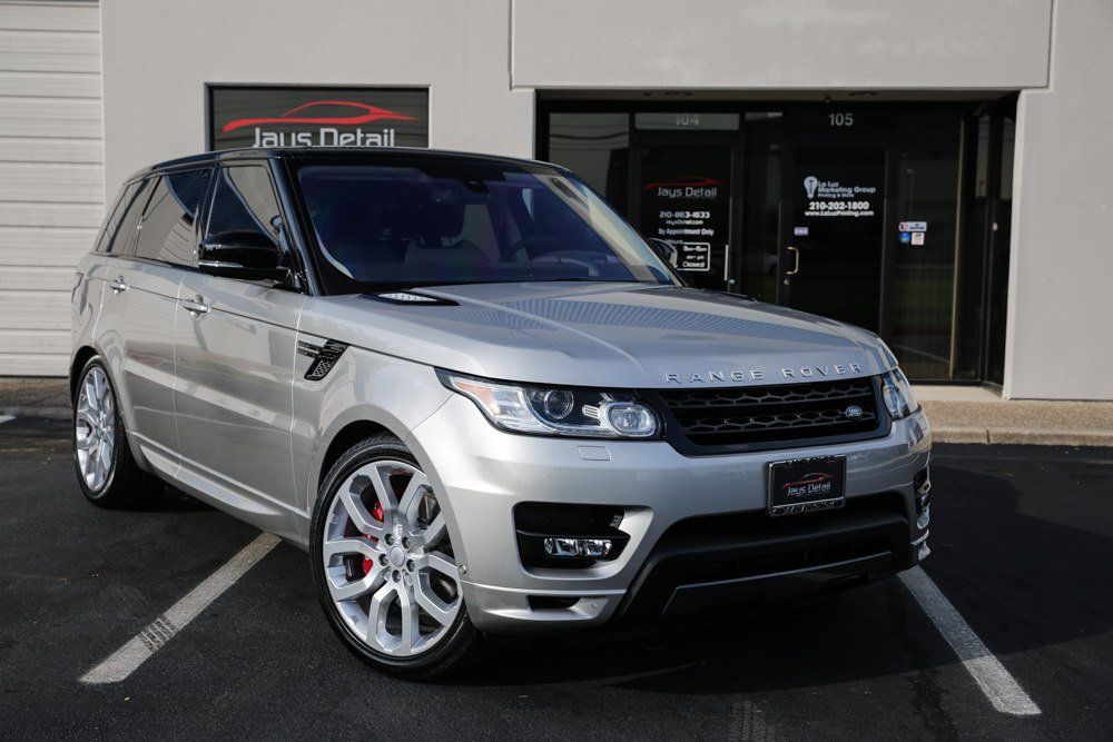 Silver Range Rover Sport parked in front of a detailing shop. Black roof, red brake calipers.