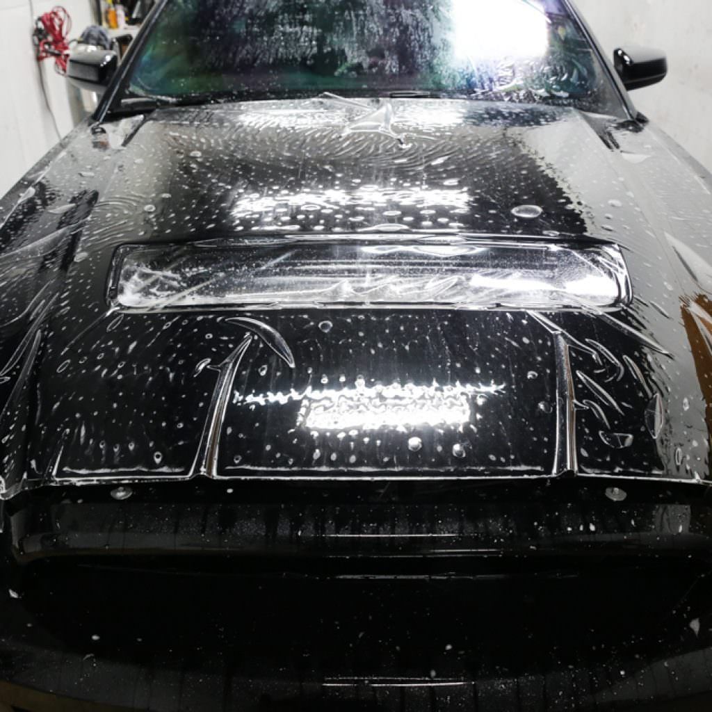 Black car hood covered in soapy water, possibly after film application.