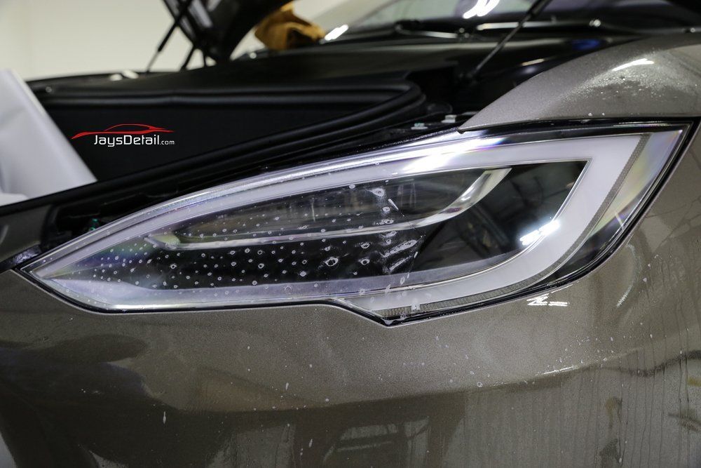 Close-up of a car headlight with a clear protective film applied.