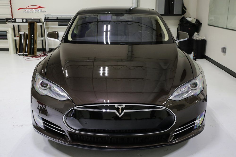 Brown Tesla sedan in a well-lit shop; front view.