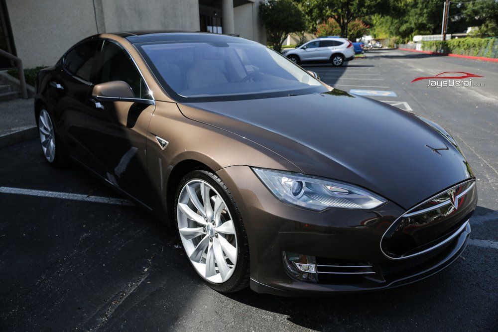 Brown Tesla Model S sedan parked in a sunny lot.