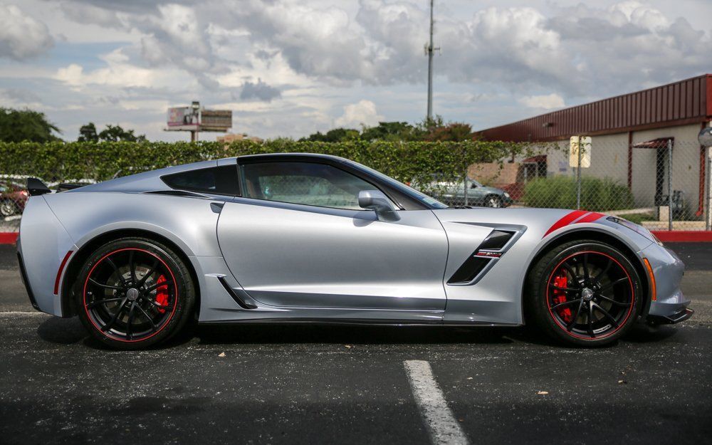 Silver sports car with red accents and black rims parked outside.