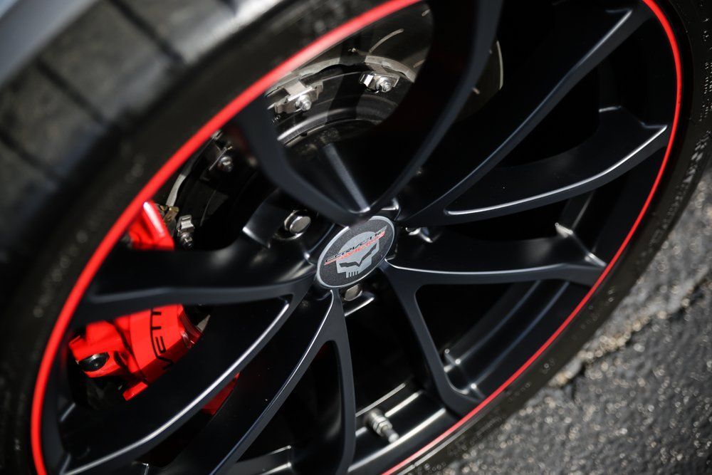 Black car wheel with a red rim and red brake caliper.