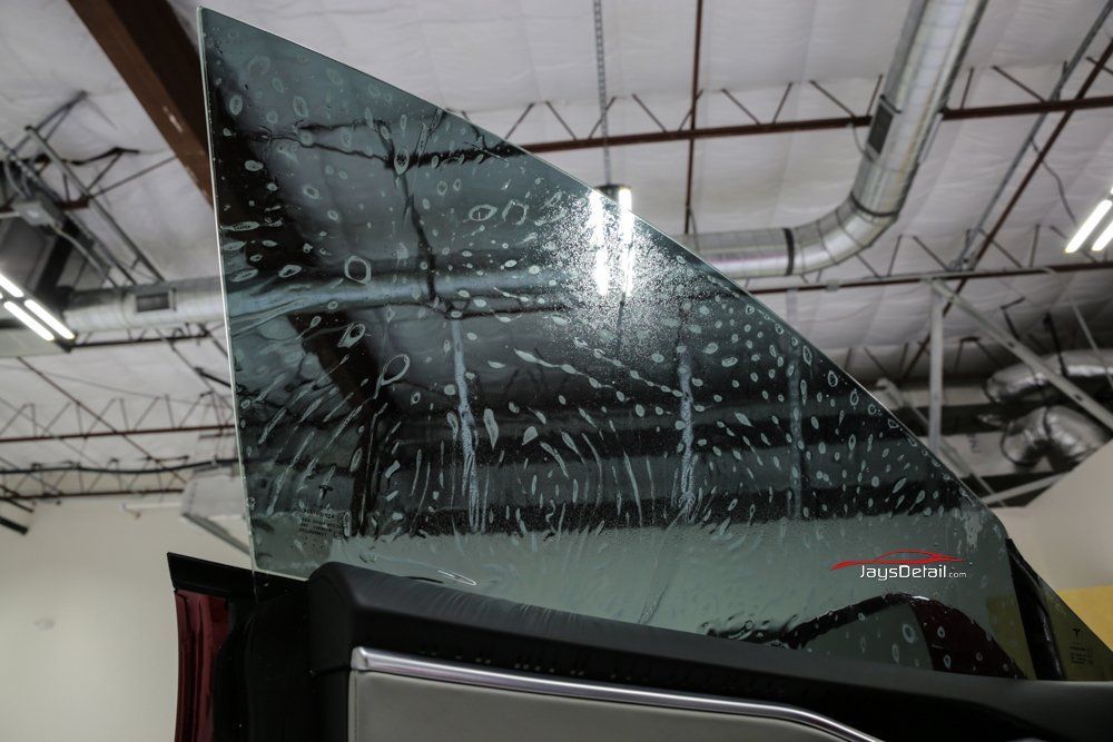 Tinted car window with water droplets, indoors.