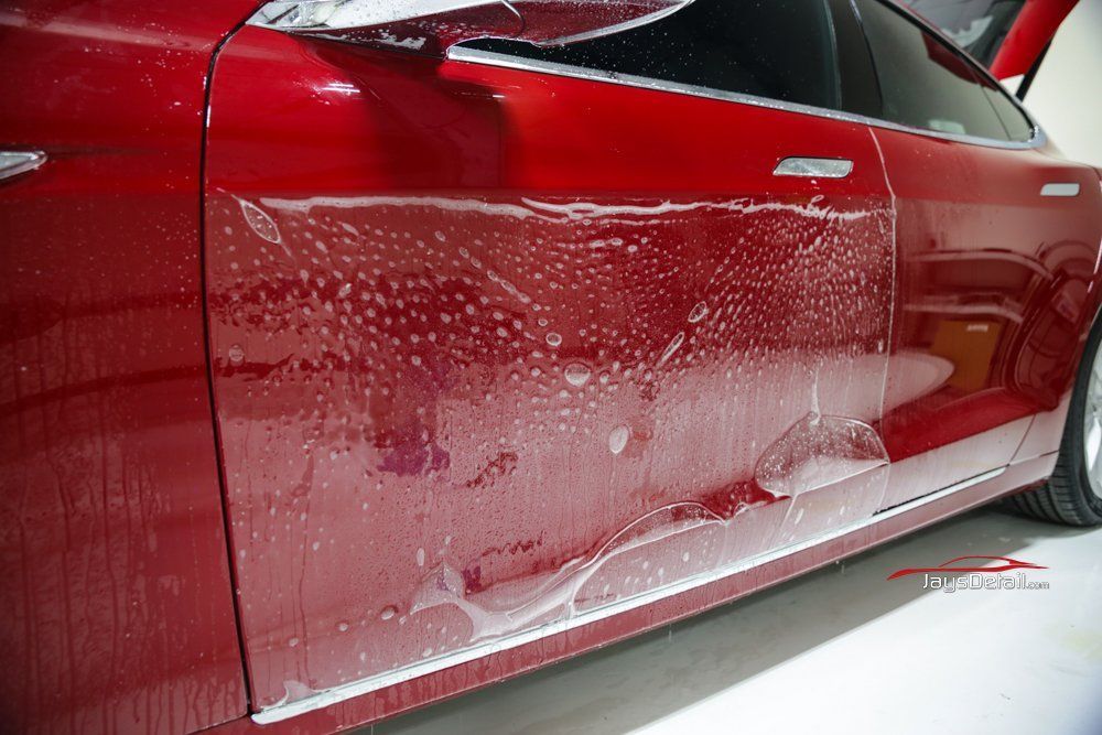 Red car with wet protective film applied to the door panel.