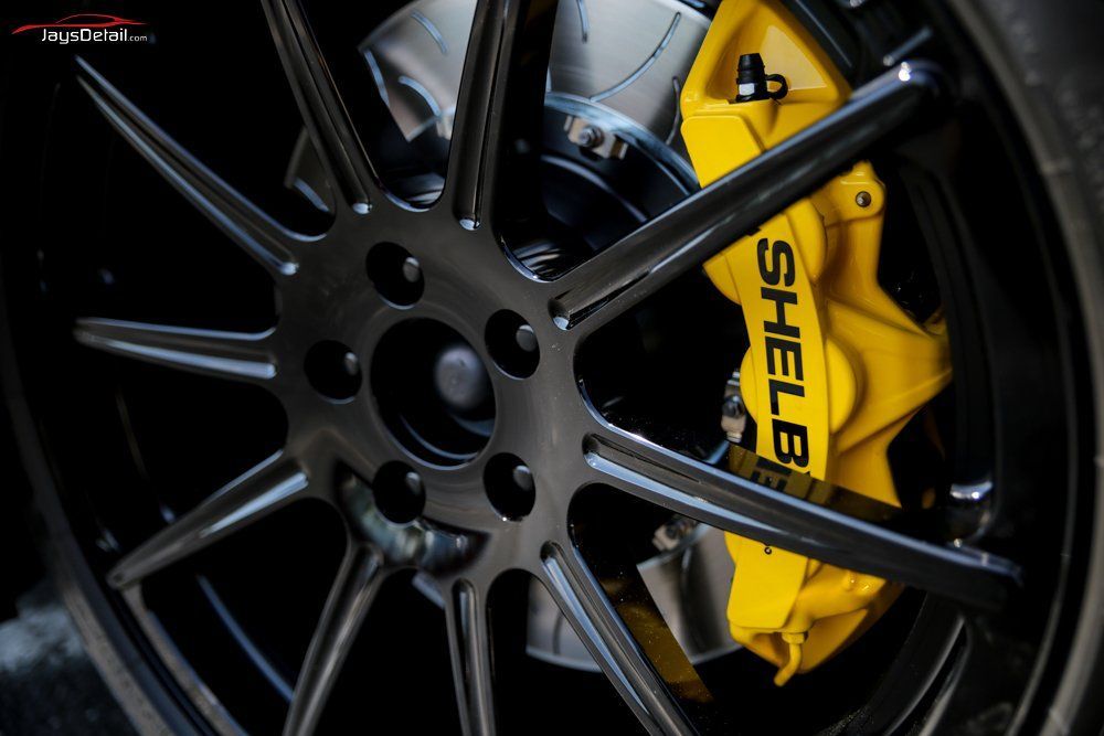 Black car wheel with yellow Shelby brake caliper.