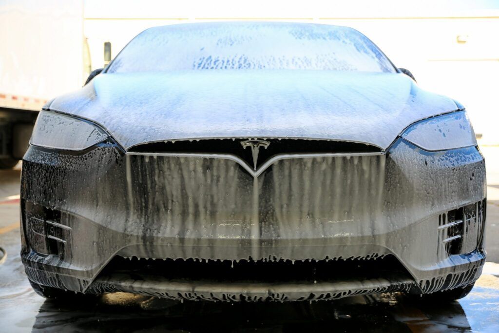 Tesla Model X covered in white car wash foam.