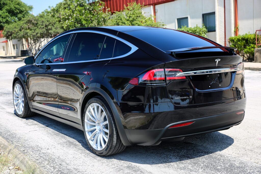 Black Tesla Model X parked outdoors with silver wheels.