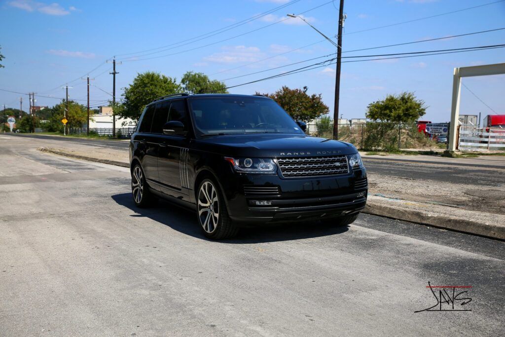 Black Range Rover SUV parked on a paved road under a clear blue sky.