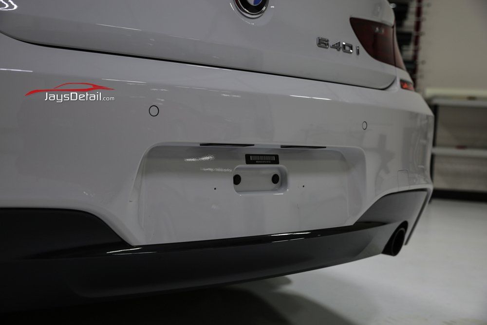 White BMW rear bumper with black accents and license plate area.