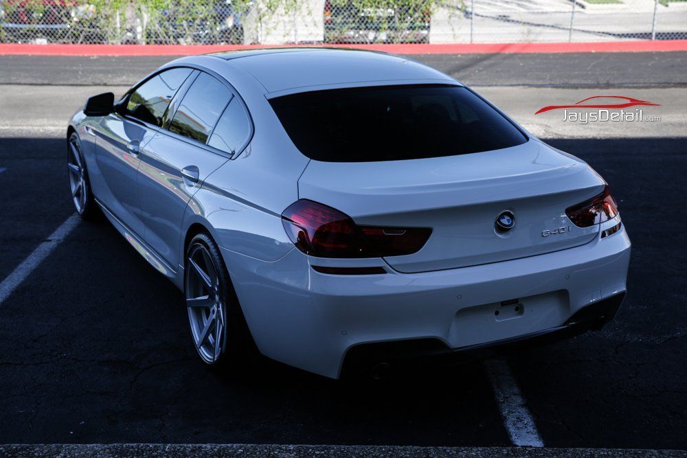 White BMW 6 Series sedan parked in a lot, angled view of rear.