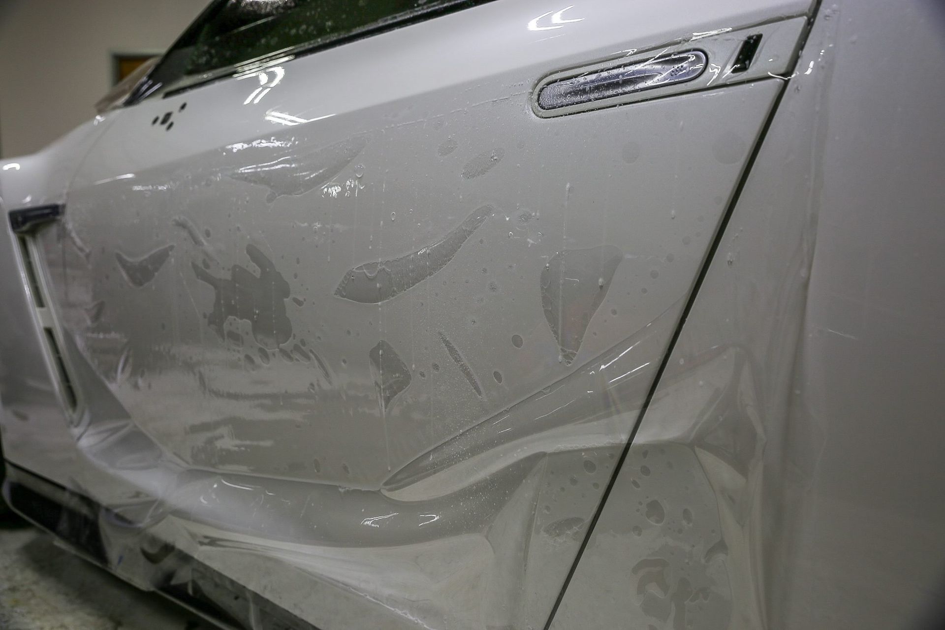 White car with protective film applied to the rear panel.