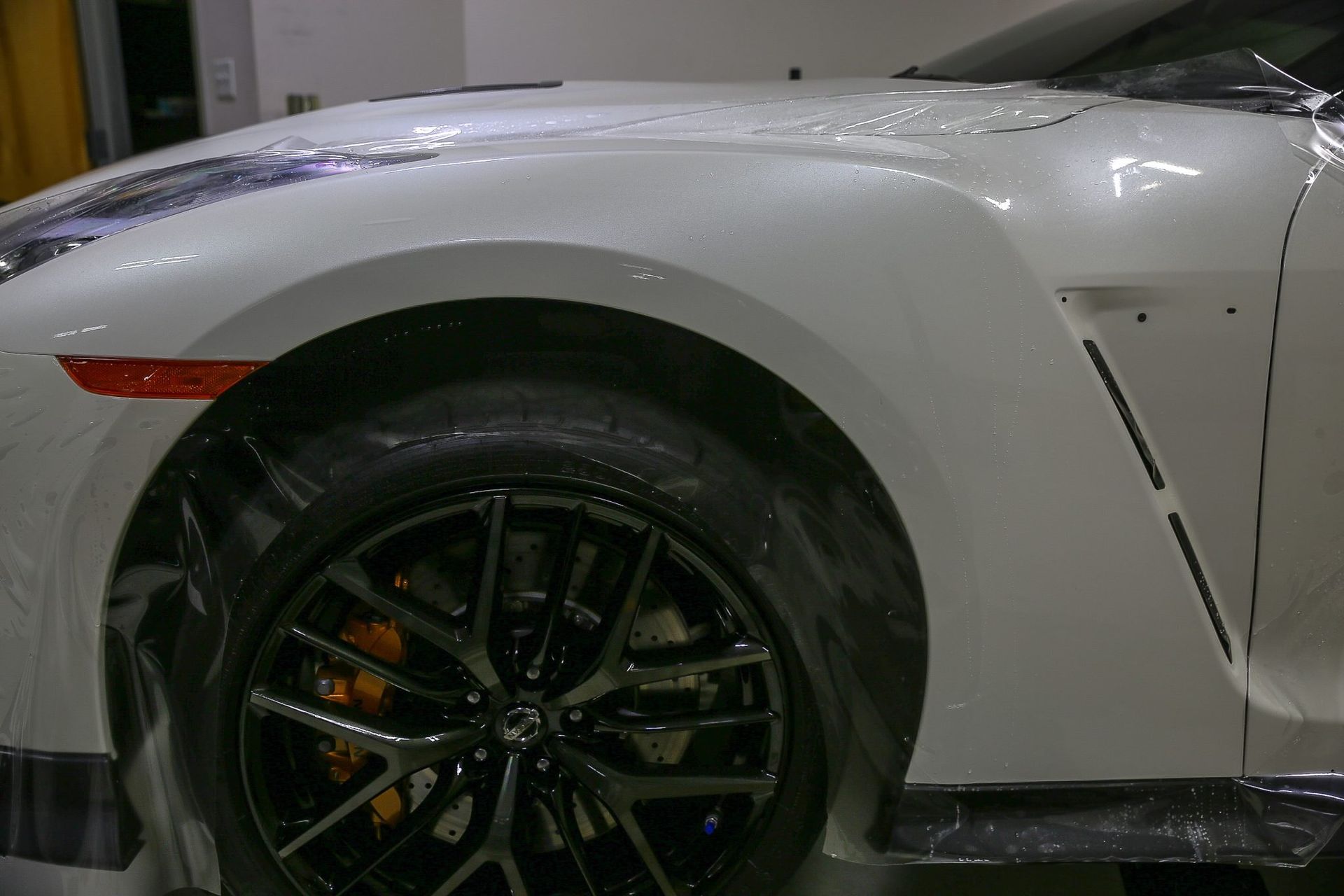 White Nissan GT-R sports car with black wheels and a front fender vent.