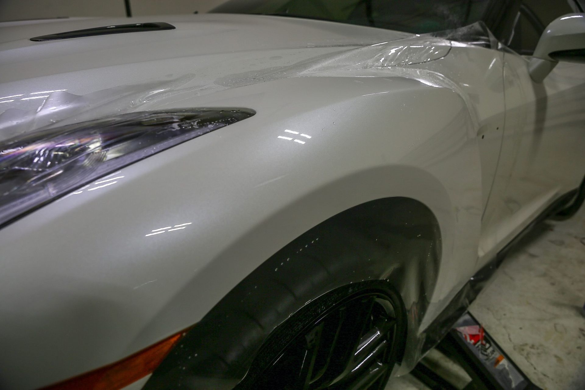White sports car's front side with a shiny finish, near its front wheel.