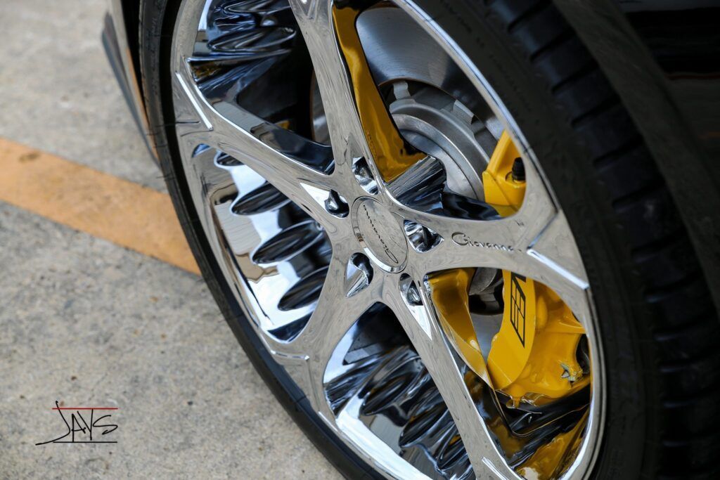 Chrome car wheel with yellow brake caliper.