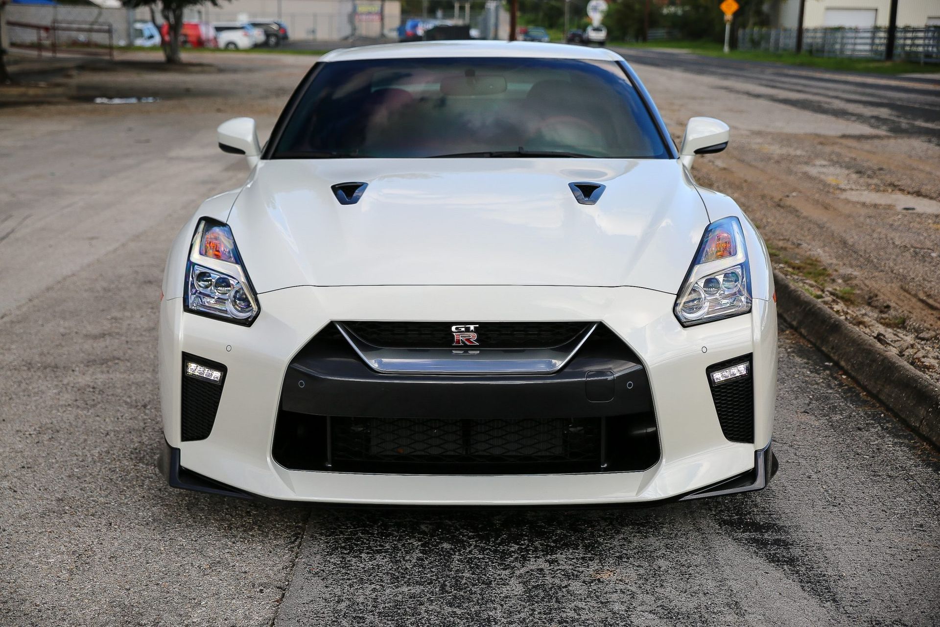 White Nissan GT-R sports car parked on asphalt, front view. Black accents on the grill and lower bumper.