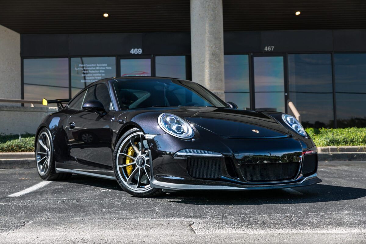 Dark gray Porsche sports car parked outside a building with dark windows.