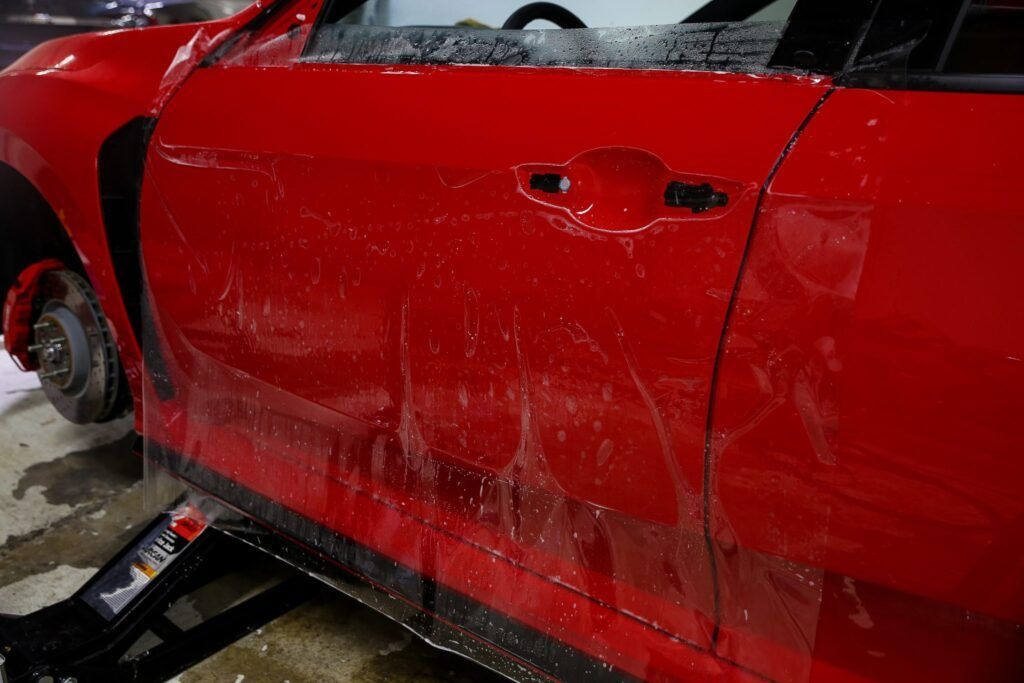 Red car door with protective film being applied.