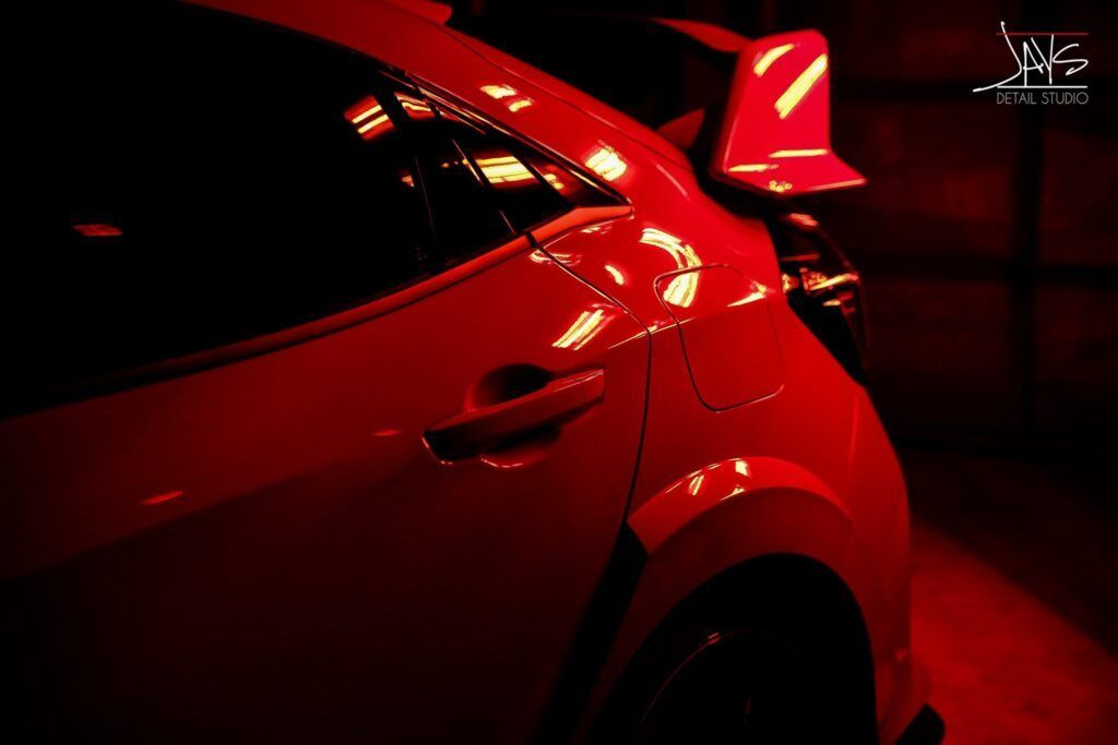 Red Honda Civic Type R in a dimly lit space, showcasing its aerodynamic design.