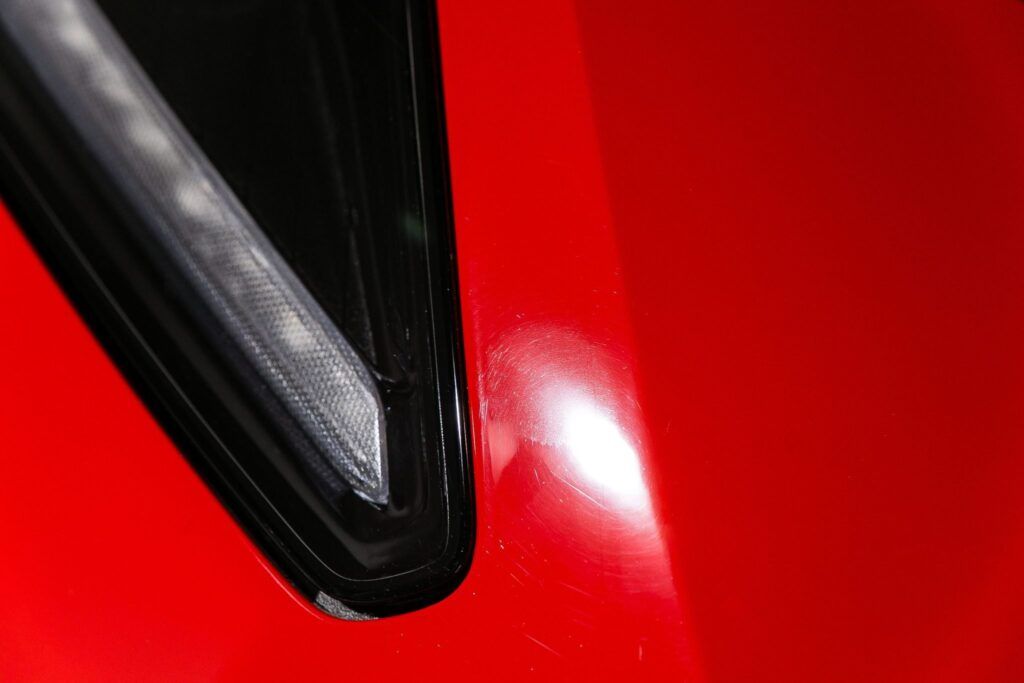 Red car body with black trim, showing a close-up of the curve and shine.