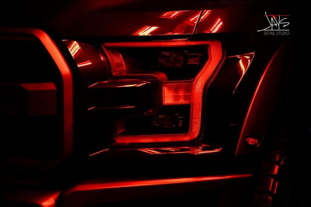 Red-lit Ford Raptor headlight detail.