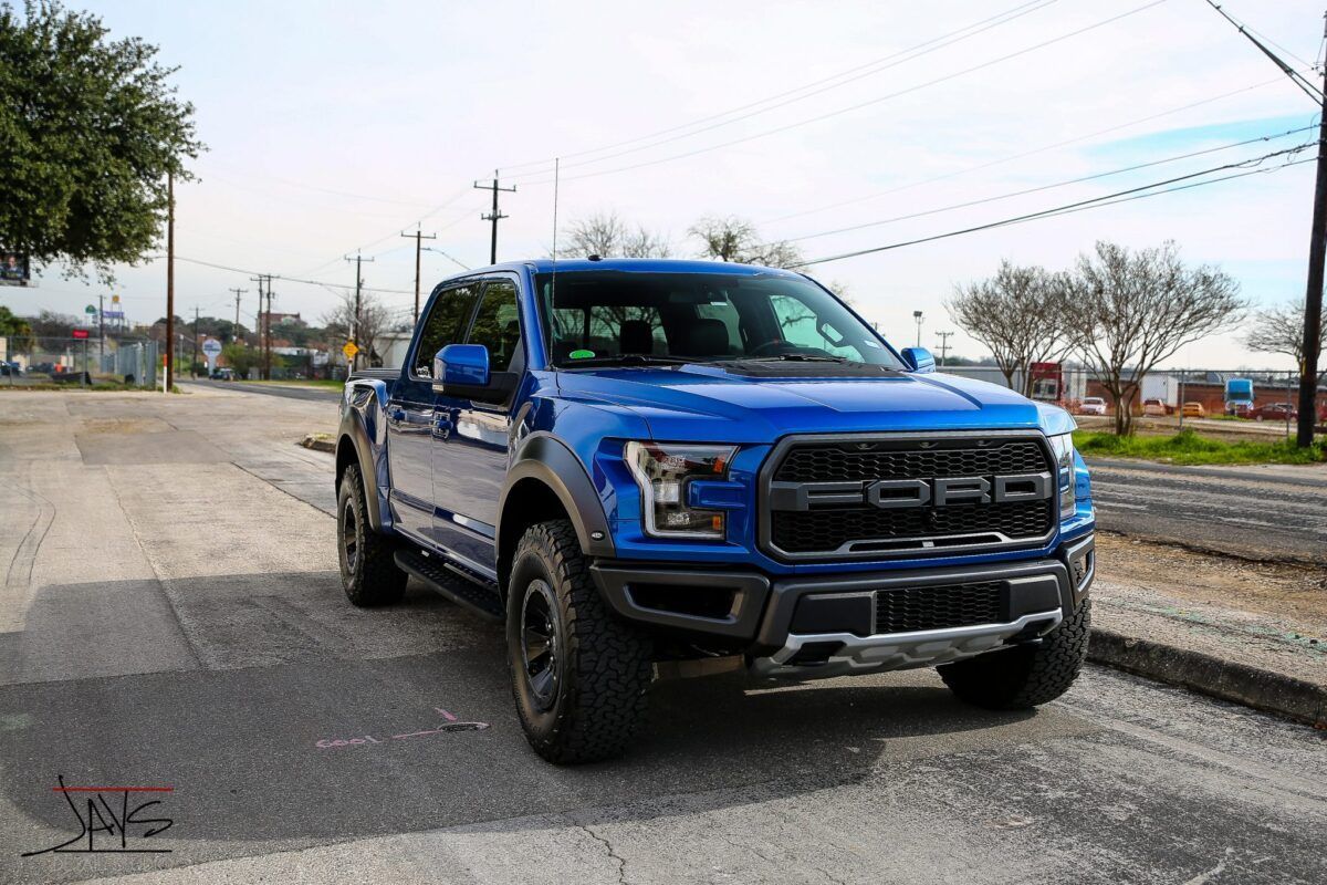 Blue Ford Raptor truck parked on a street; sunny day.