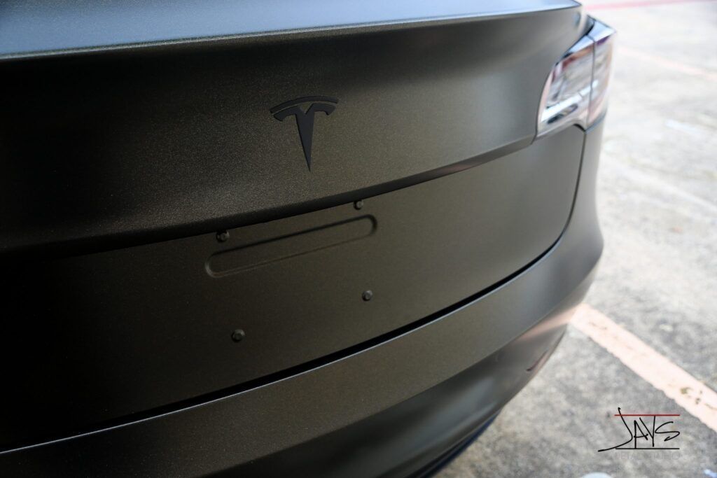 Matte black Tesla Model 3 rear with logo and license plate area.