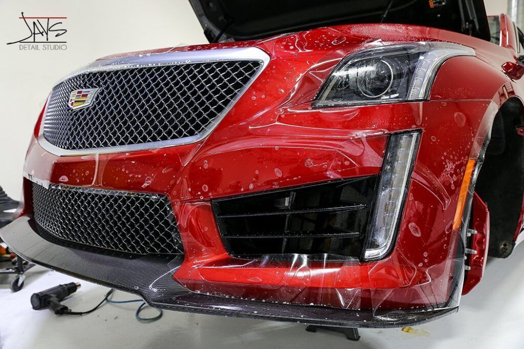 Red Cadillac being wrapped in clear protective film.