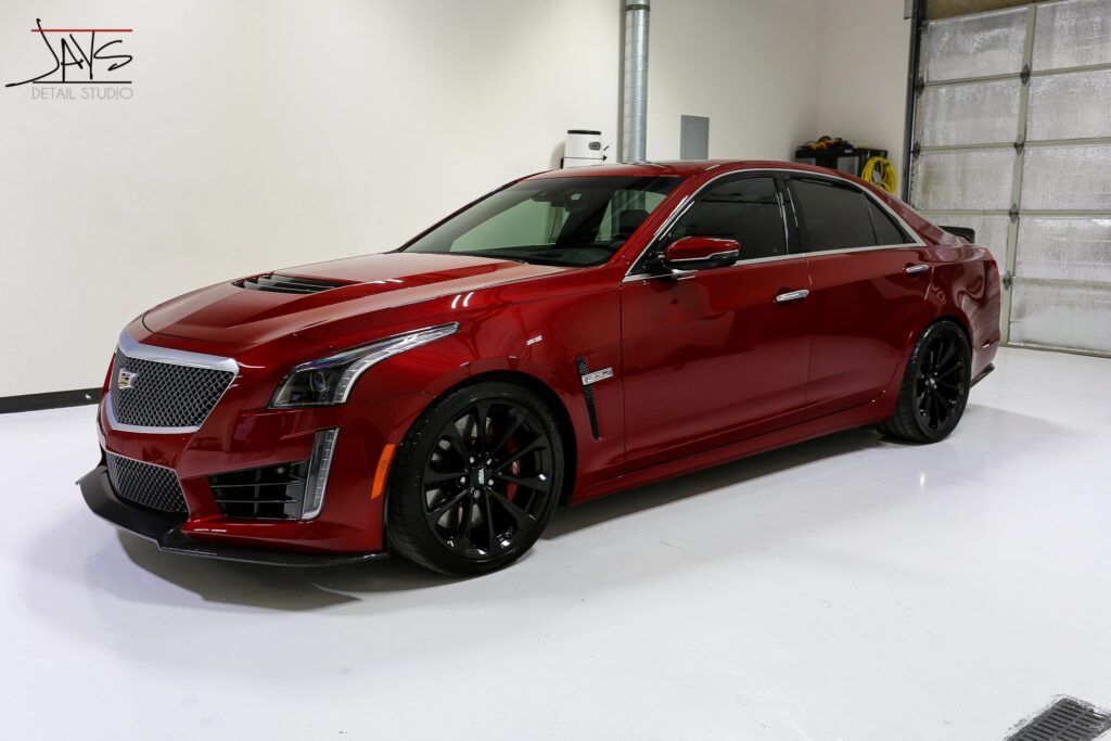 Red Cadillac CTS-V sedan with black wheels parked inside a garage.