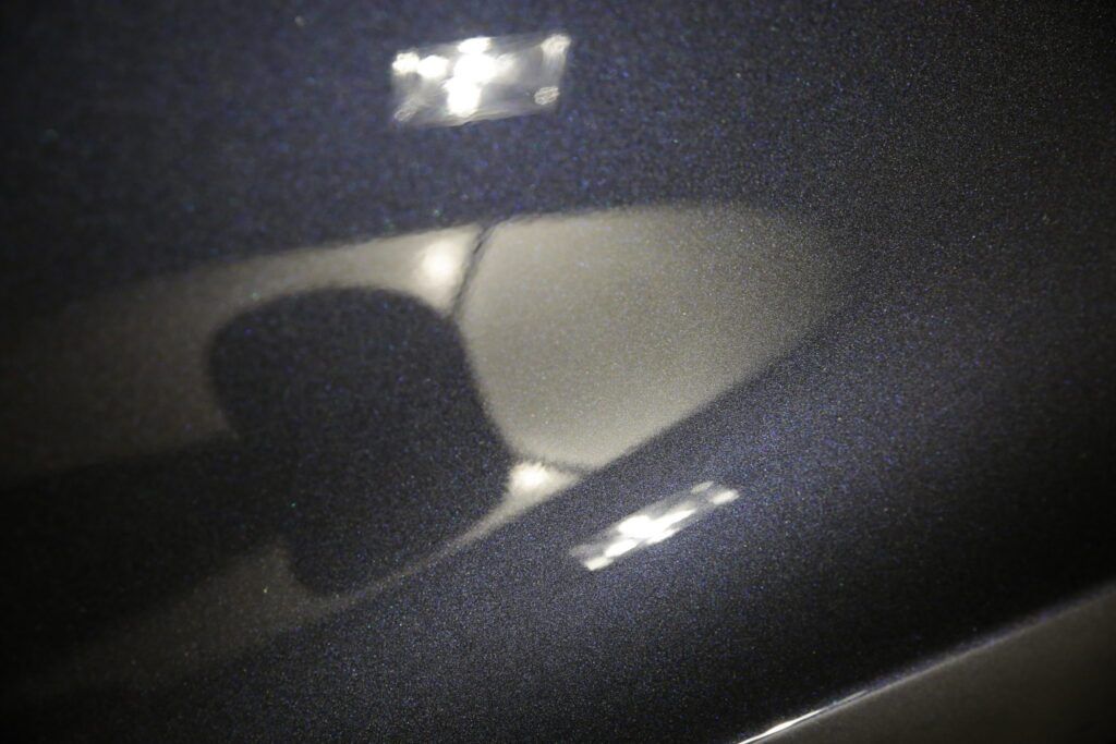 Dark blue car interior with reflected lights and a speaker grill.