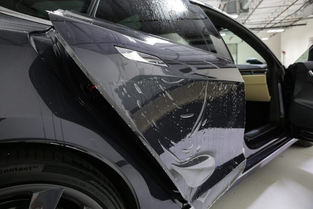 Dark car door with a film being applied.