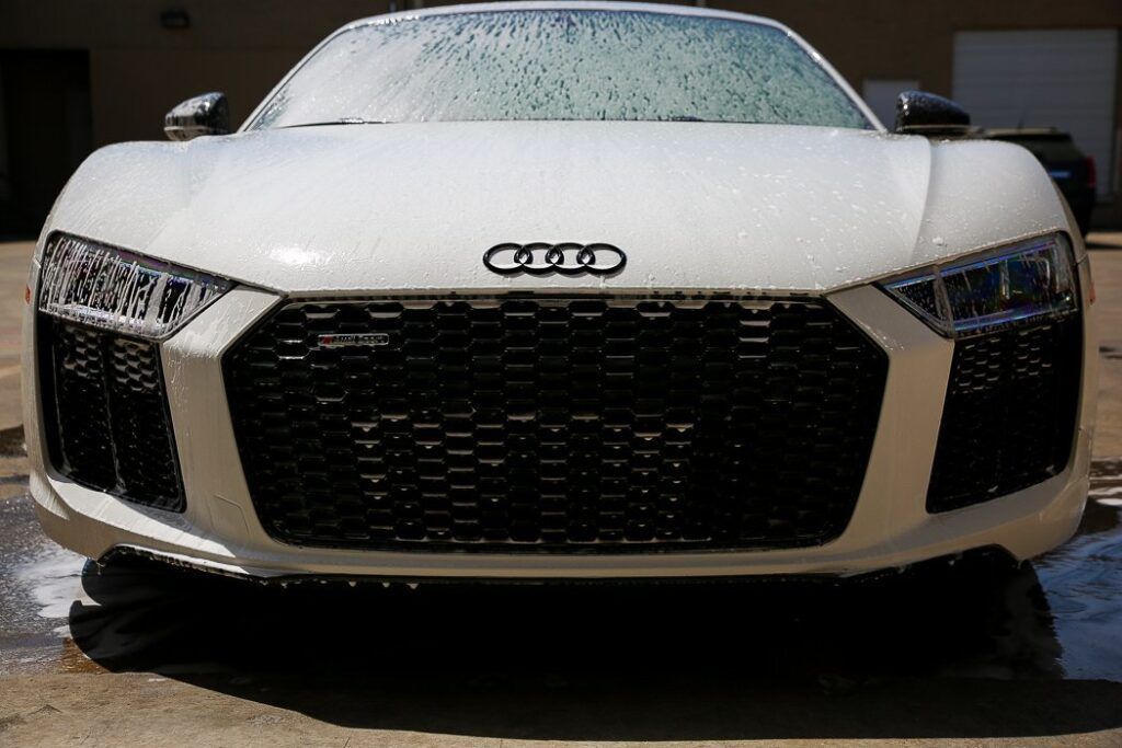 White Audi R8 getting washed, suds on the front, black grill.