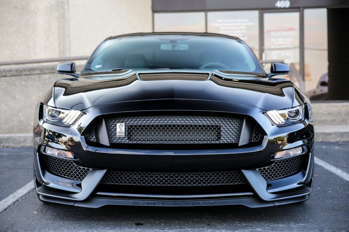 Black Mustang sports car parked in front of a building, front view.