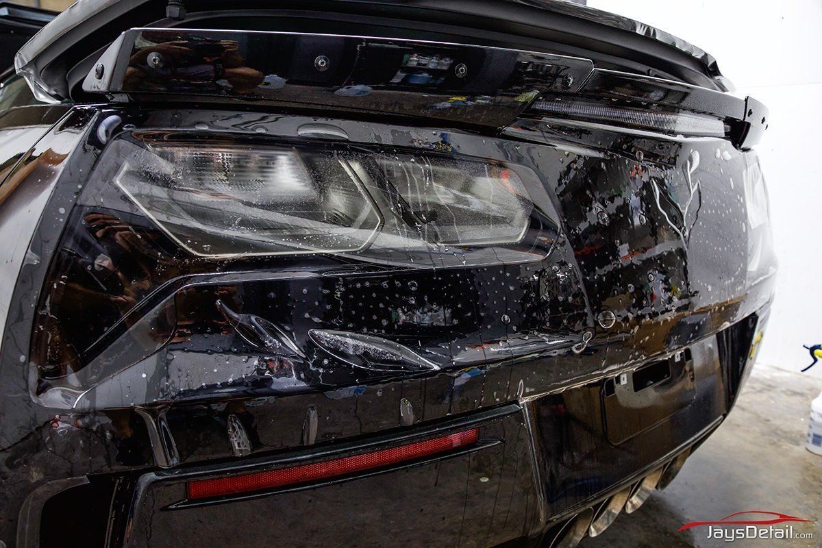 Black car taillight with wet protective film being applied.