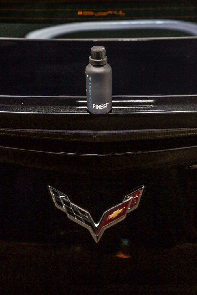 Black car rear with Chevy logo, black bottle on top.