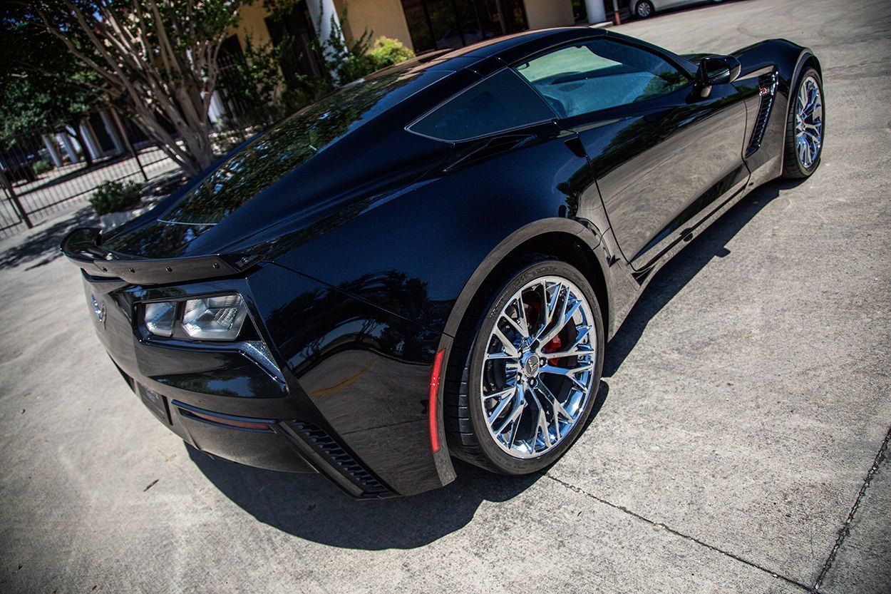 Black Chevrolet Corvette parked on a gray concrete surface.