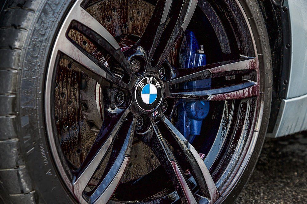 Close-up of a BMW car wheel with a black rim, silver accents, and blue brake caliper.