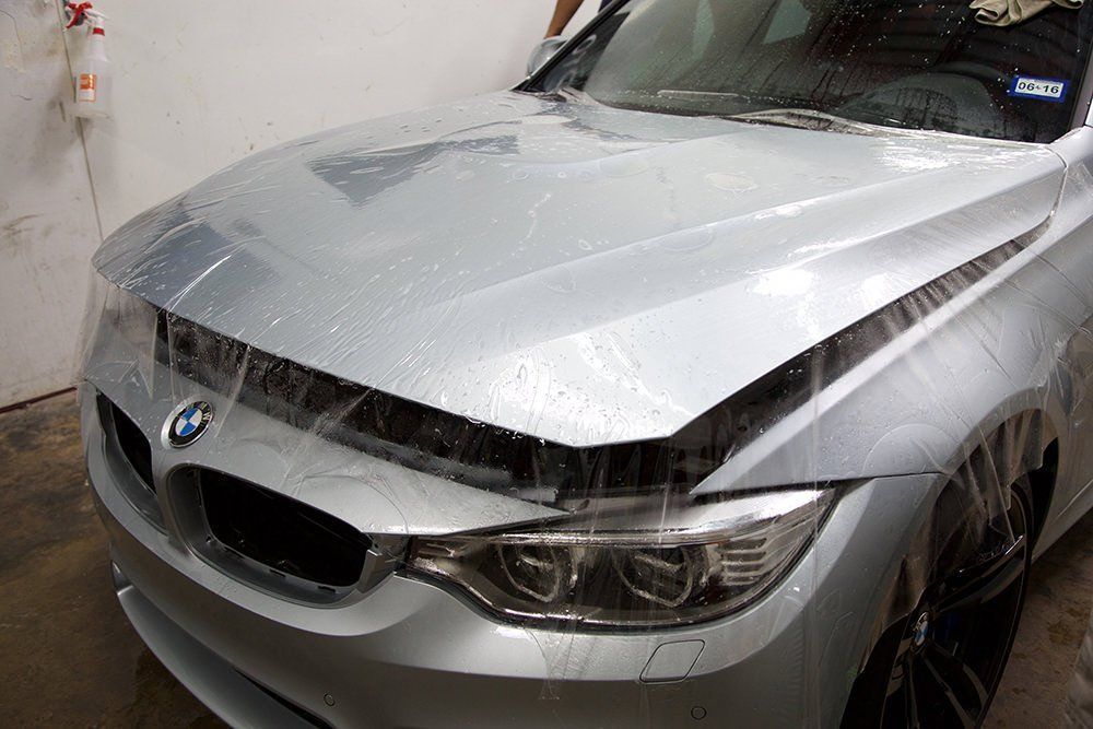 Silver BMW being covered with protective film.