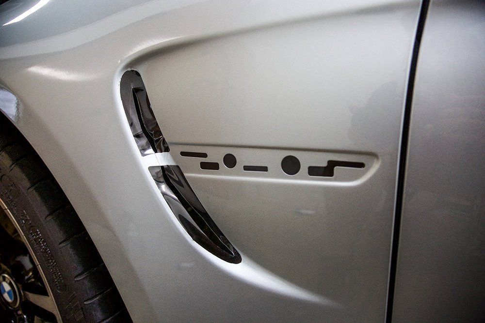 Silver car fender with side vent and black accents.