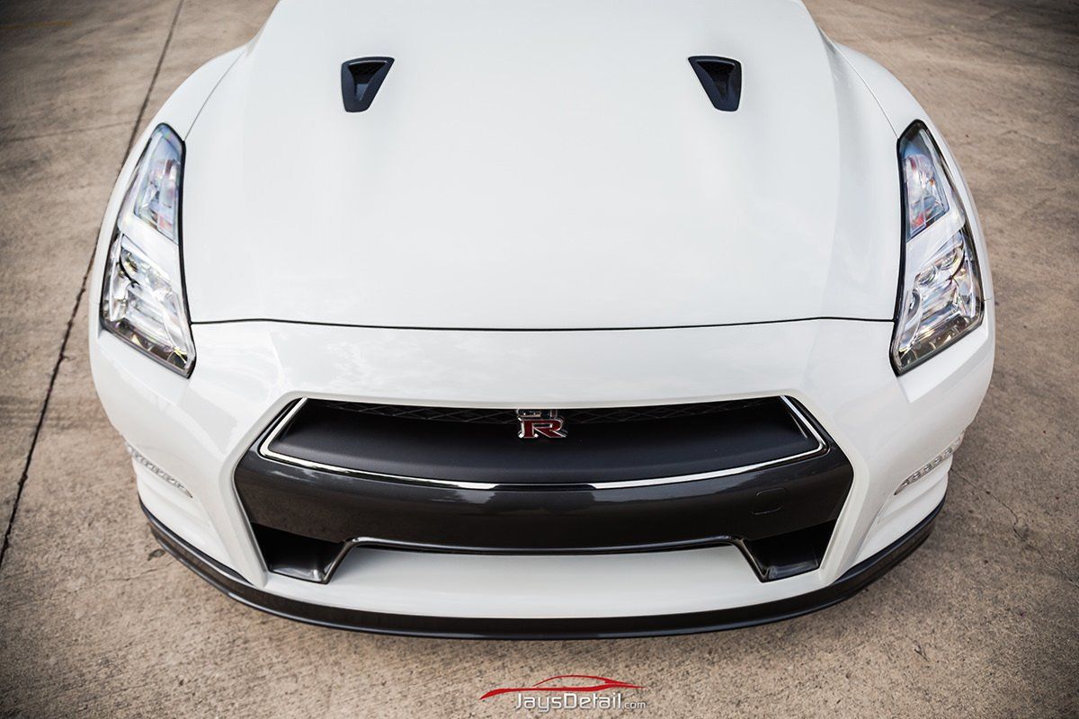 White Nissan GT-R sports car, front view, on asphalt. Black grill and vents.