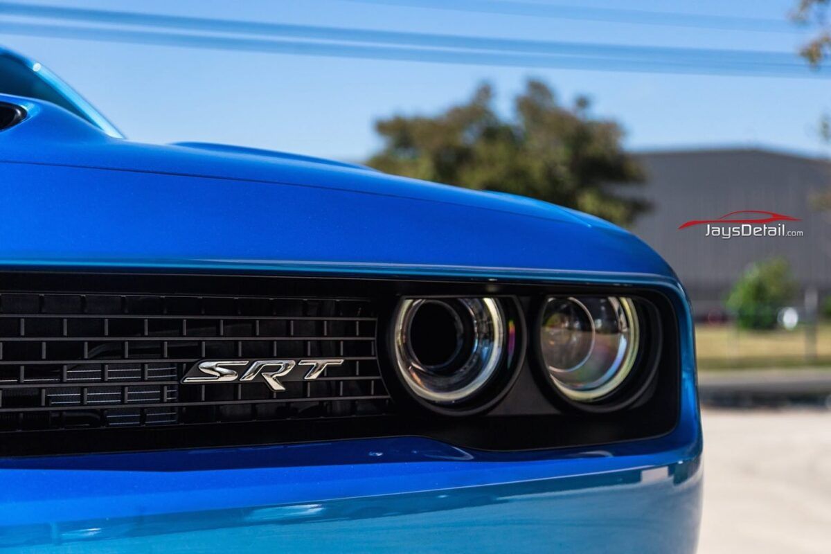 Blue Dodge Challenger SRT, close-up view of front grille, headlights, and hood.
